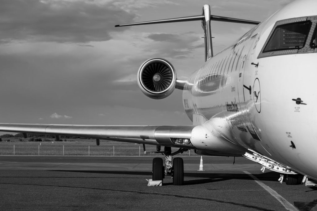 Monochrome photo of a commercial jet airplane taken from the side at an airport.